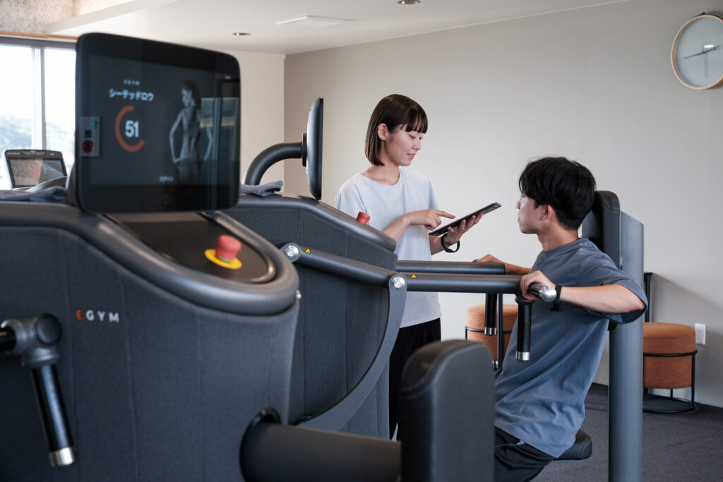 スタッフがタブレットでEGYMの設定を確認している
